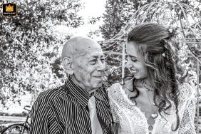 Bride and Grandfather Share a Special Moment at Forlì's Ca Freschi Reception Venue Forlì's Ca Freschi reception venue provides the backdrop for this wedding day. The bride and her grandfather stand side by side, smiling and sharing a secret moment as they pose outdoors among the trees.
